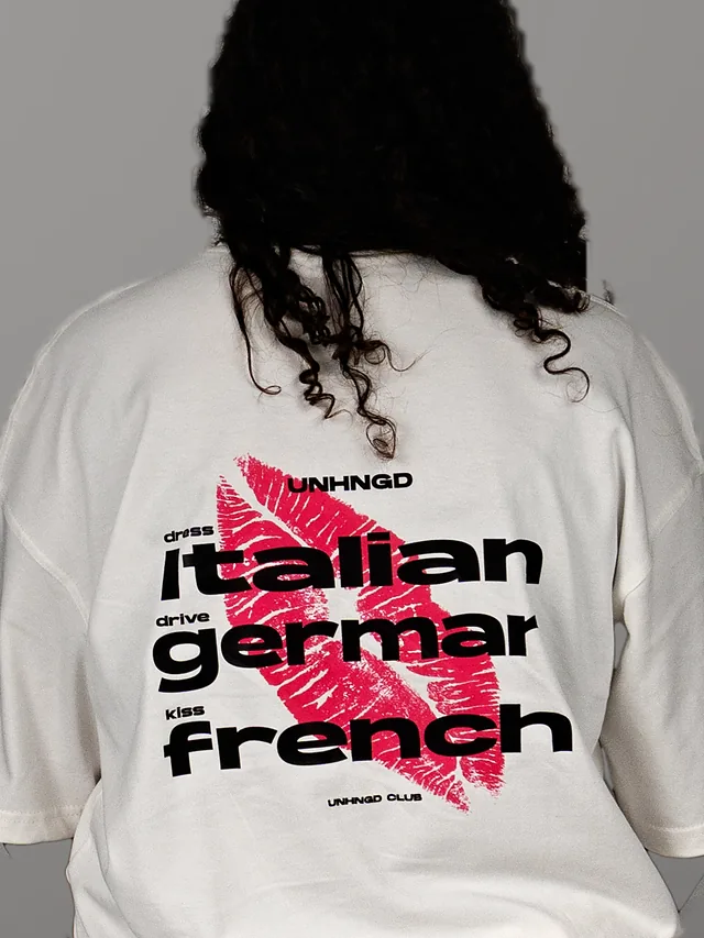 The ‘Dress Italian, drive German, kiss French’ print with a pink lipstick kiss, on the back of a white tee.